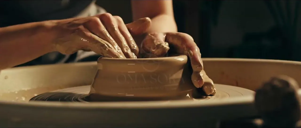 Video ad still, hands shaping clay